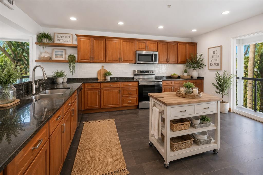 A kitchen with wood cabinets, dark granite countertops, a mobile island, and a balcony view — 2738 JOHN BULL STREET, FLAGLER BEACH, FL