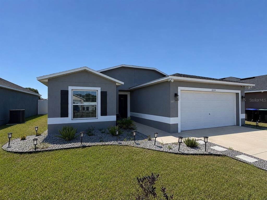 A single-story house with a gray exterior, a two-car garage, and a landscaped front yard — 7259 HOLLY CREEK ROAD, MOUNT DORA, FL