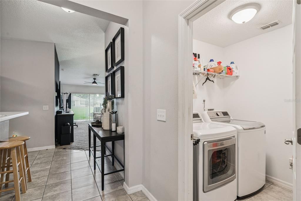 A laundry room with a washer and dryer sits beside a hallway with a console table — 7259 HOLLY CREEK ROAD, MOUNT DORA, FL
