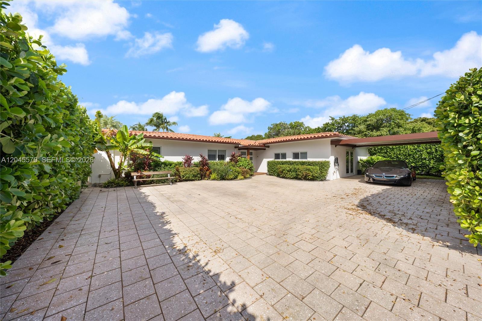 A single-story house with a tiled roof features a paved driveway and a covered carport — 12944 Banyan Rd, North Miami FL 33181, NORTH MIAMI, FL