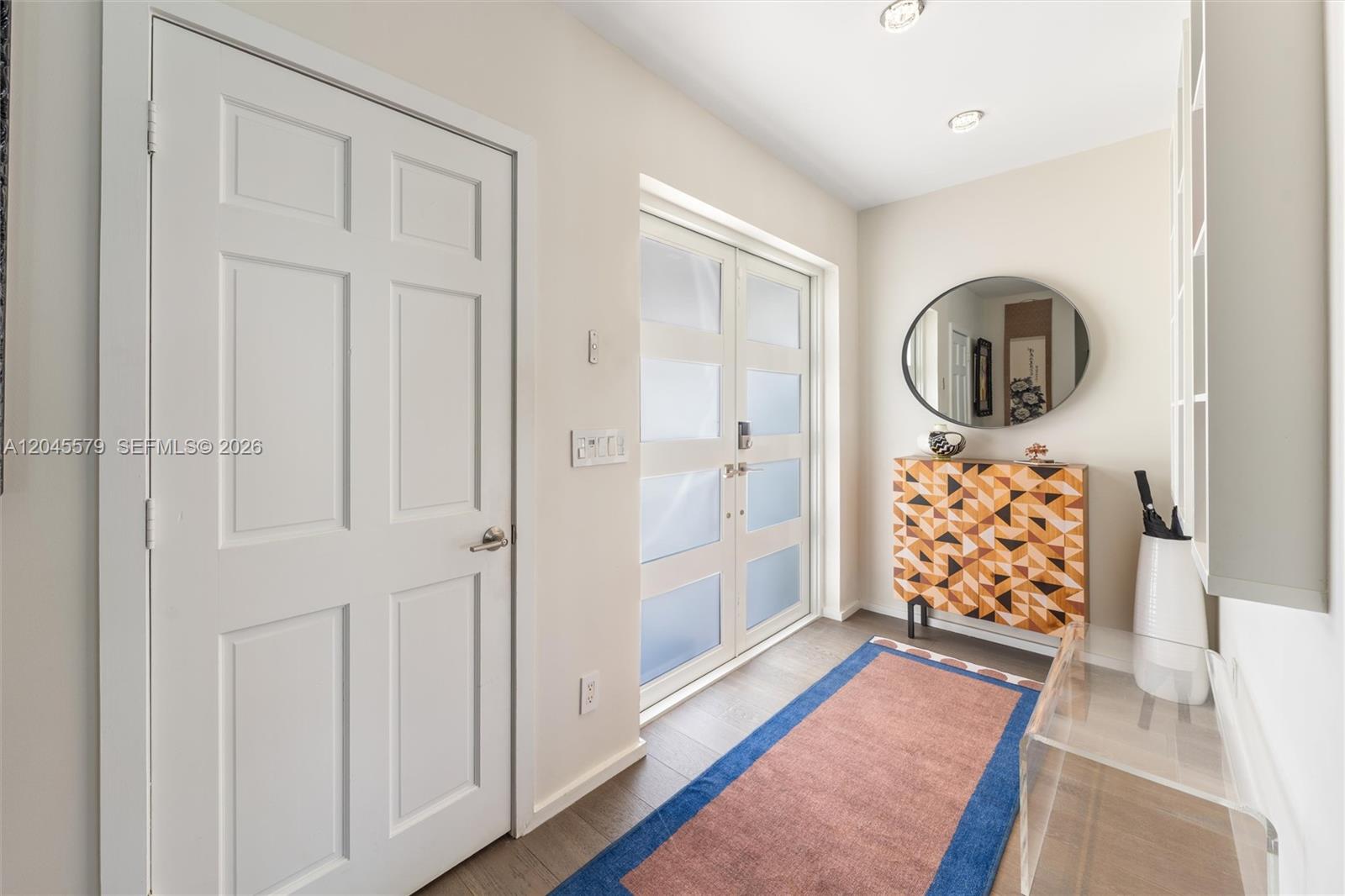 A bright entryway features a geometric cabinet, a round mirror, and a colorful area rug — 12944 Banyan Rd, North Miami FL 33181, NORTH MIAMI, FL