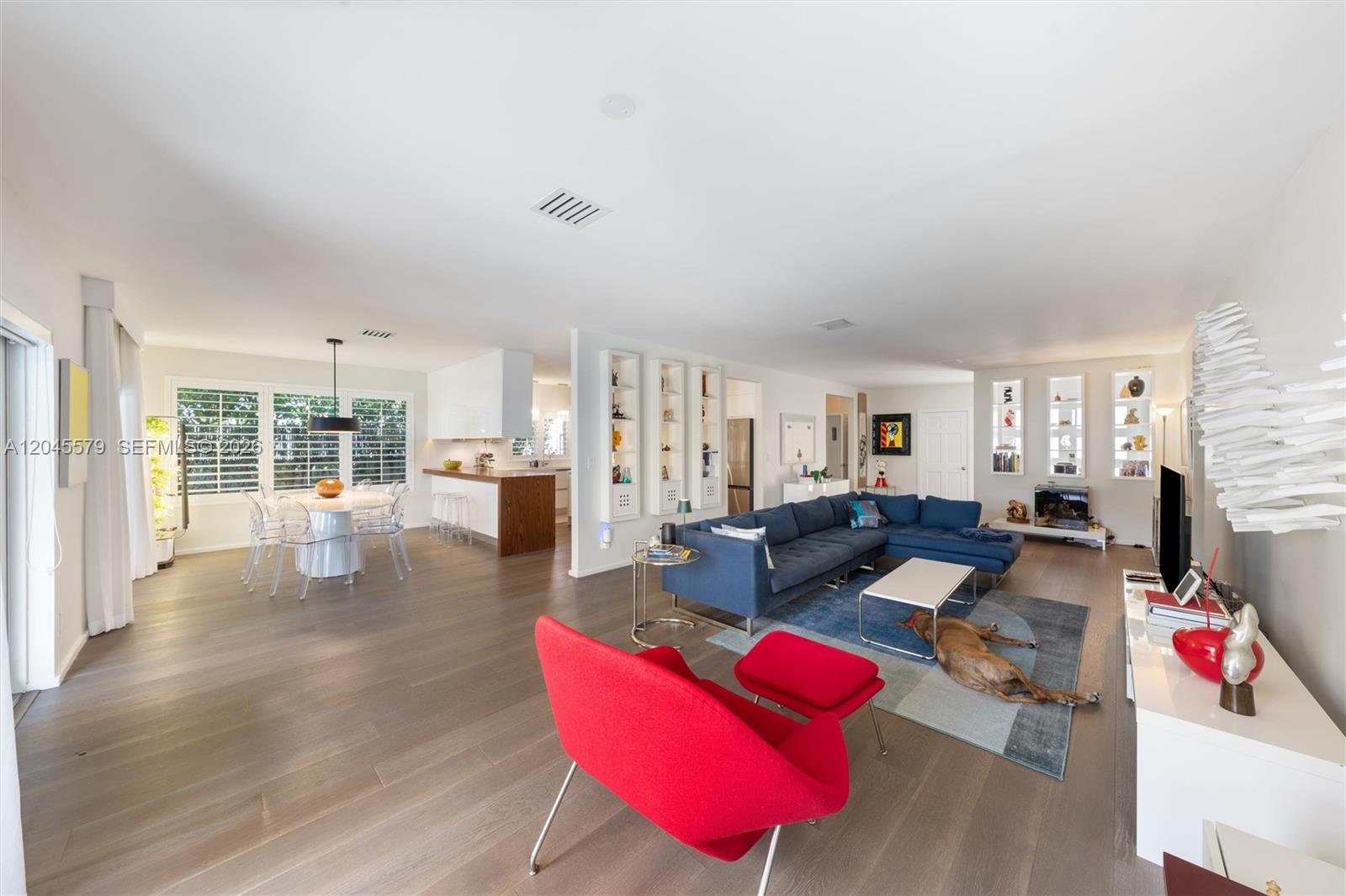 A bright, open-concept living and dining area features hardwood floors, a blue sectional, and furniture — 12944 Banyan Rd, North Miami FL 33181, NORTH MIAMI, FL