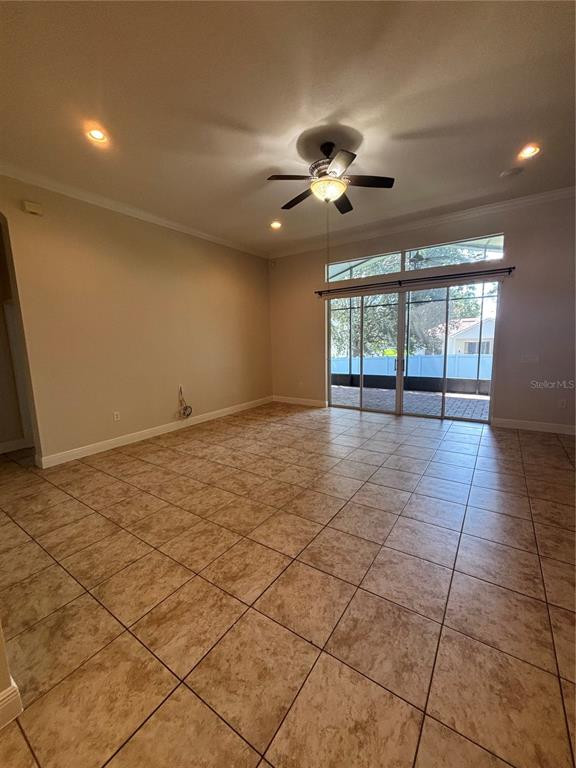 An empty living room features tile flooring, a ceiling fan, and sliding glass patio doors — 3650 PEACE PIPE WAY, CLERMONT, FL