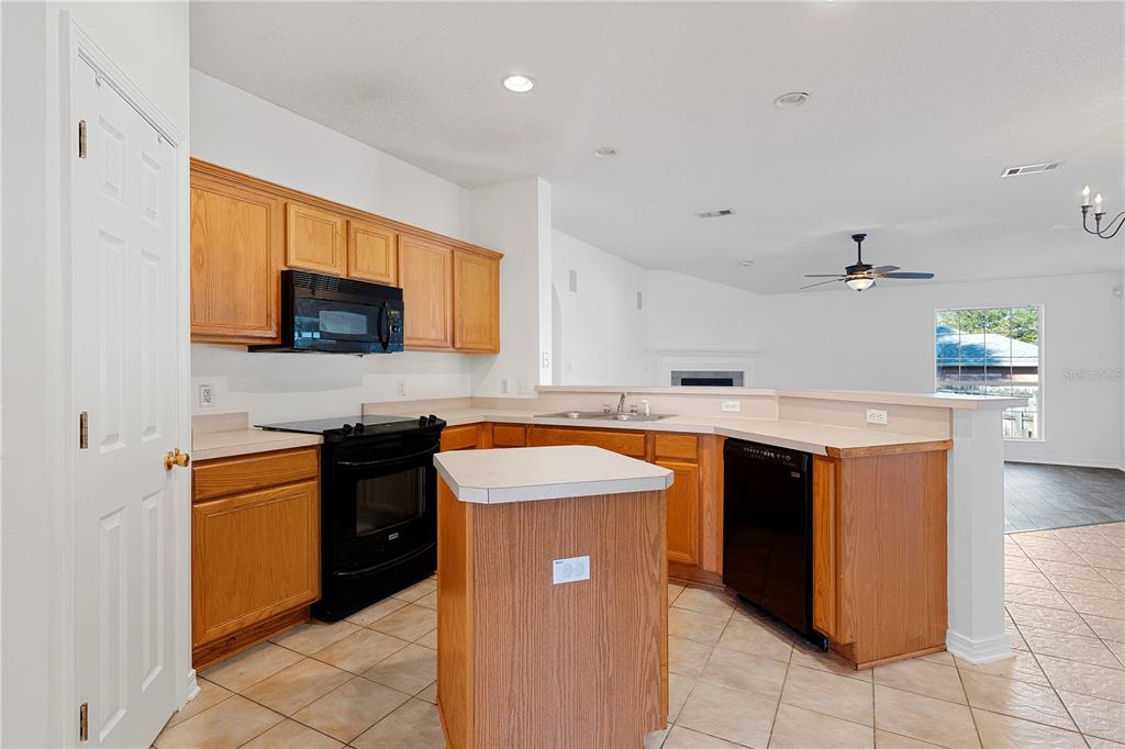 A kitchen features oak cabinets, black appliances, a central island, and tile flooring — 6622 HALLENDALE DRIVE, PENSACOLA, FL