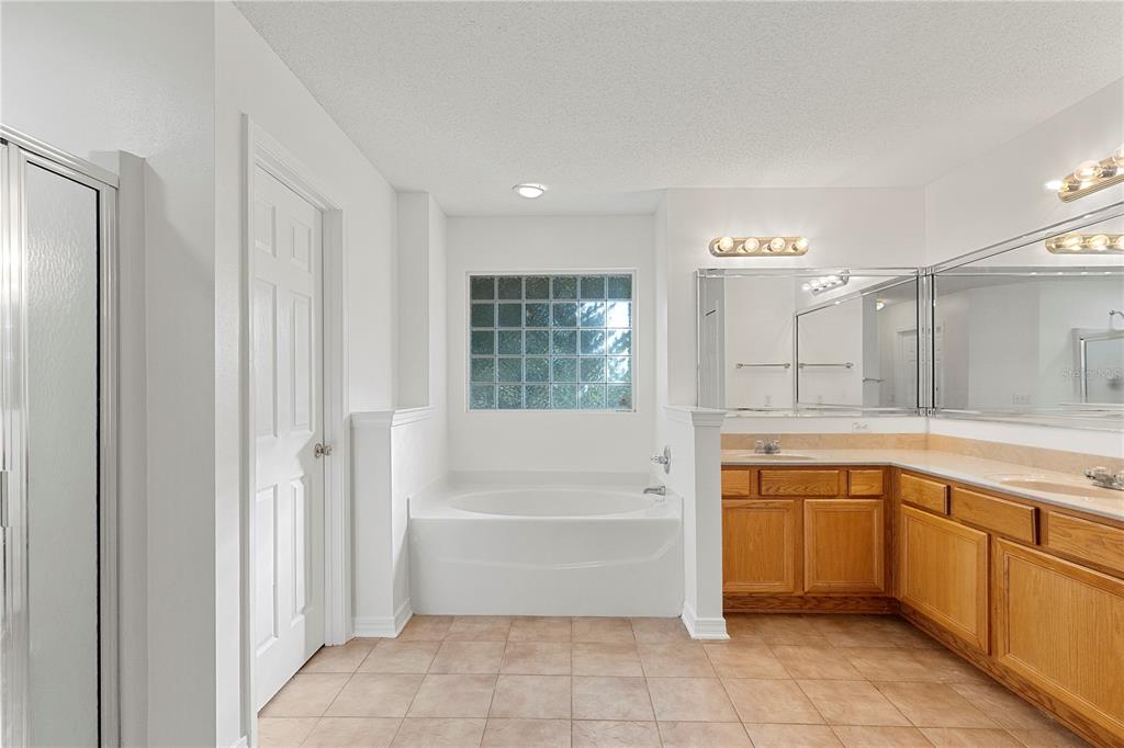 A bathroom features a soaking tub, a double vanity with wood cabinets, and tile flooring — 6622 HALLENDALE DRIVE, PENSACOLA, FL