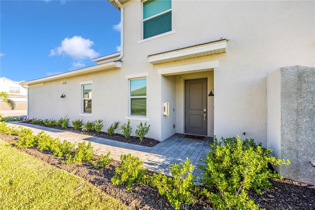 The exterior of a two-story house features a gray front door and a paved walkway — 17640 BORACAY COURT UNIT 102, VENICE, FL