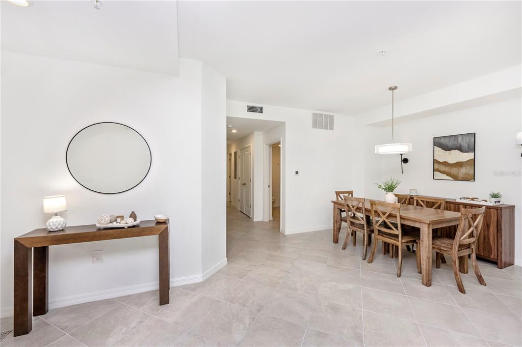 A dining area and entryway feature light tile floors, white walls, and wood furniture — 17640 BORACAY COURT UNIT 102, VENICE, FL