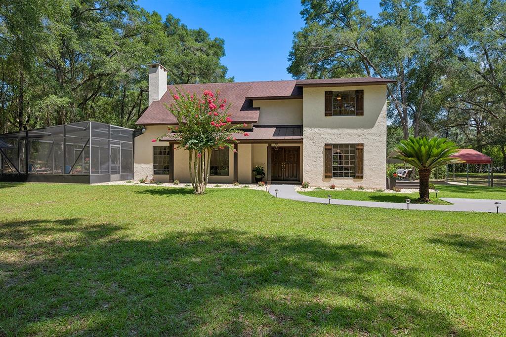 A two-story stucco house with a screened-in pool area and a large front lawn — 22110 SW 15TH AVENUE, NEWBERRY, FL