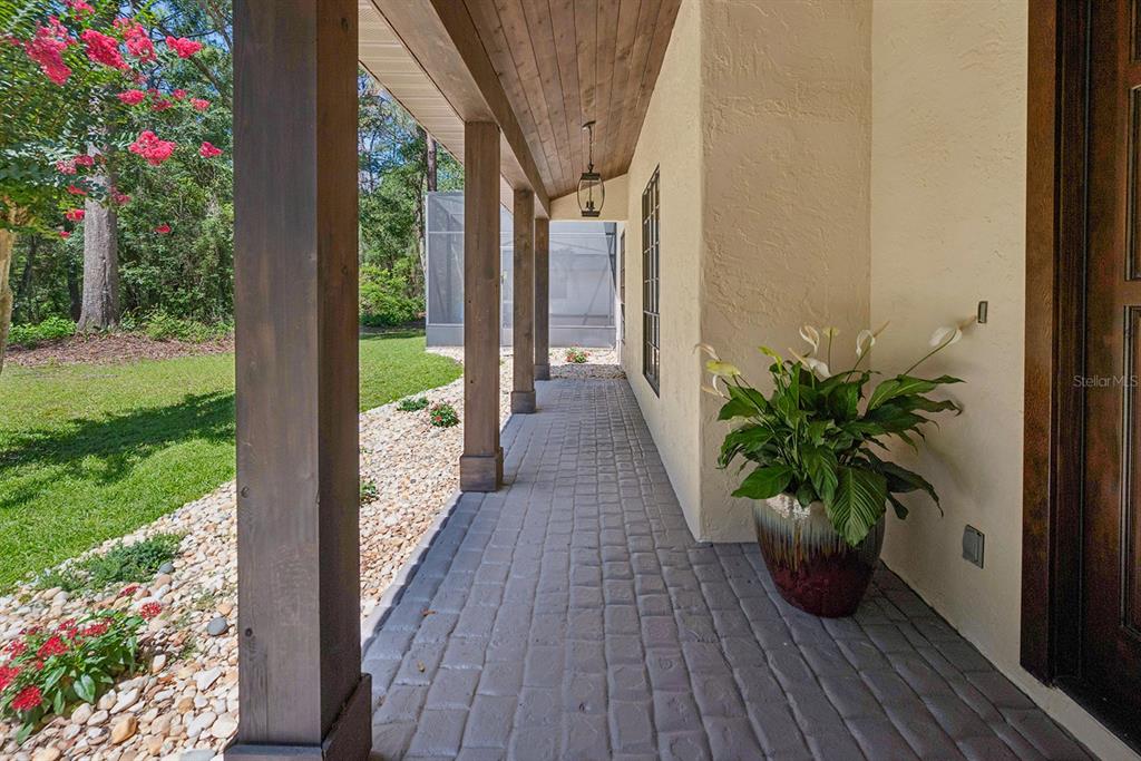A covered porch features a stone-paver floor, wooden support columns, and a potted plant — 22110 SW 15TH AVENUE, NEWBERRY, FL