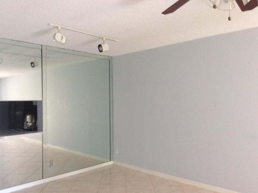 A room features a large mirrored wall, light-colored tile flooring, and a track lighting fixture — 300 NE 26th Avenue NE # 1040, Boynton Beach FL 33435, BOYNTON BEACH, FL