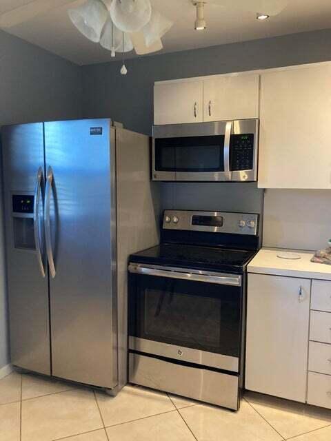 A kitchen features stainless steel appliances, white cabinets, and light-colored tile flooring — 300 NE 26th Avenue NE # 1040, Boynton Beach FL 33435, BOYNTON BEACH, FL
