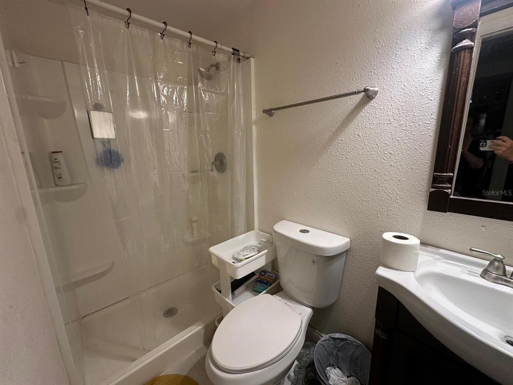A bathroom features a shower-tub combination, a white toilet, and a vanity with a mirror — 10040 62ND STREET N, PINELLAS PARK, FL