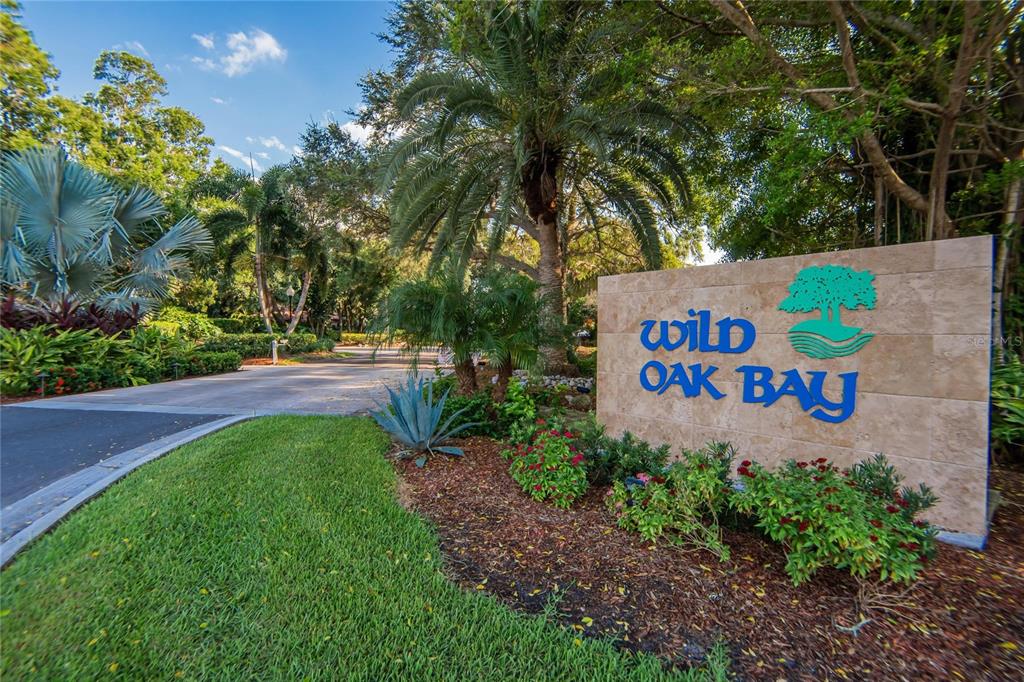 A stone monument sign for Wild Oak Bay stands beside a paved entrance road — 3415 WILD OAK BAY BOULEVARD UNIT 427, BRADENTON, FL