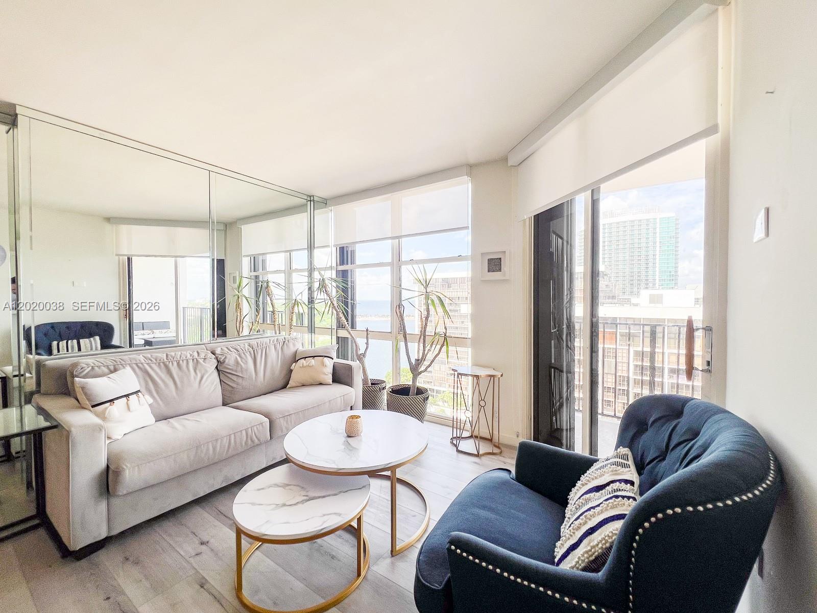 An empty room features light wood flooring, mirrored walls, and large windows overlooking city buildings — 1901 Brickell Ave # B2004, Miami FL 33129, MIAMI, FL