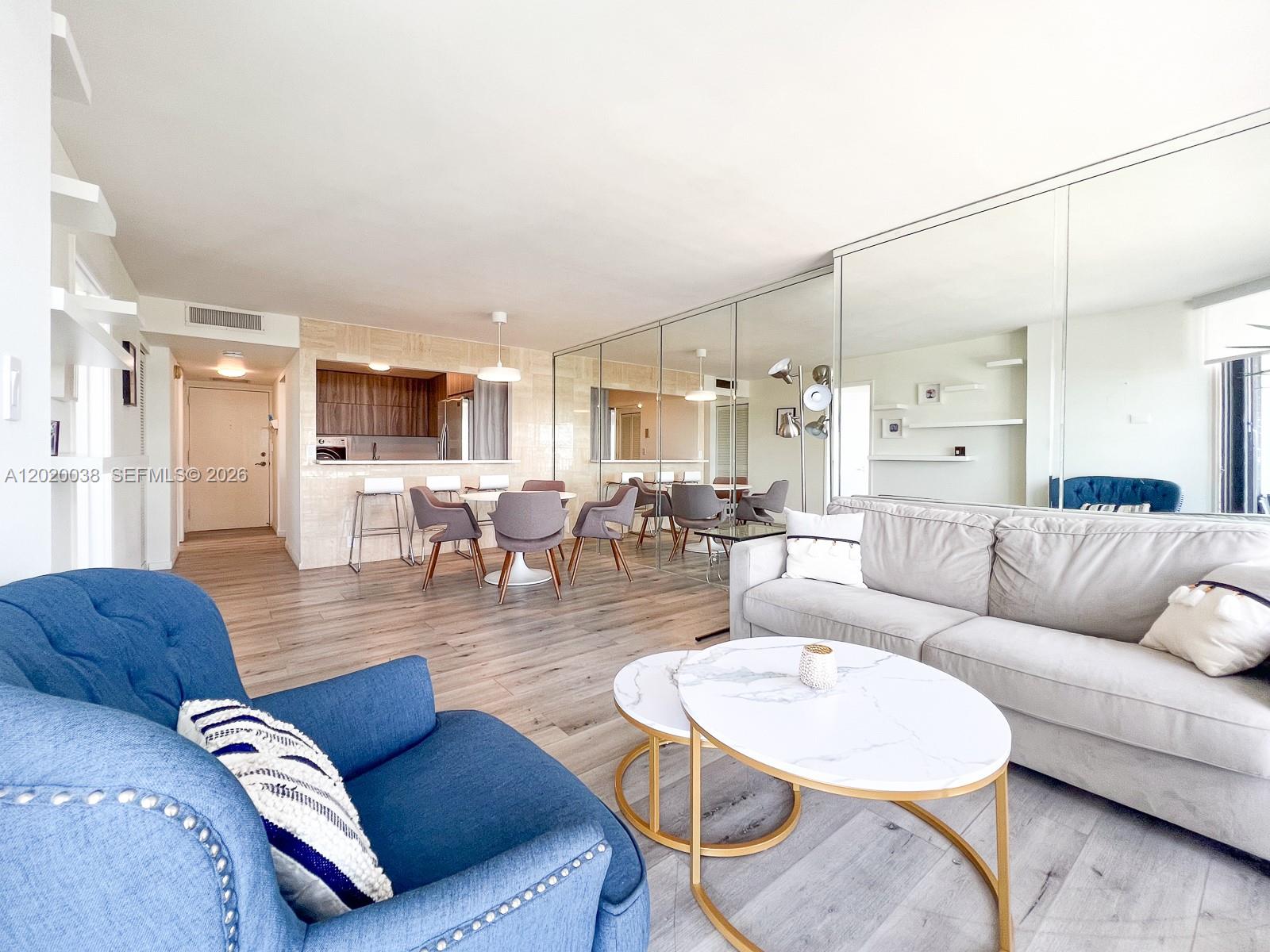 A living room with light wood floors, a sectional sofa, and a wall-mounted television — 1901 Brickell Ave # B2004, Miami FL 33129, MIAMI, FL