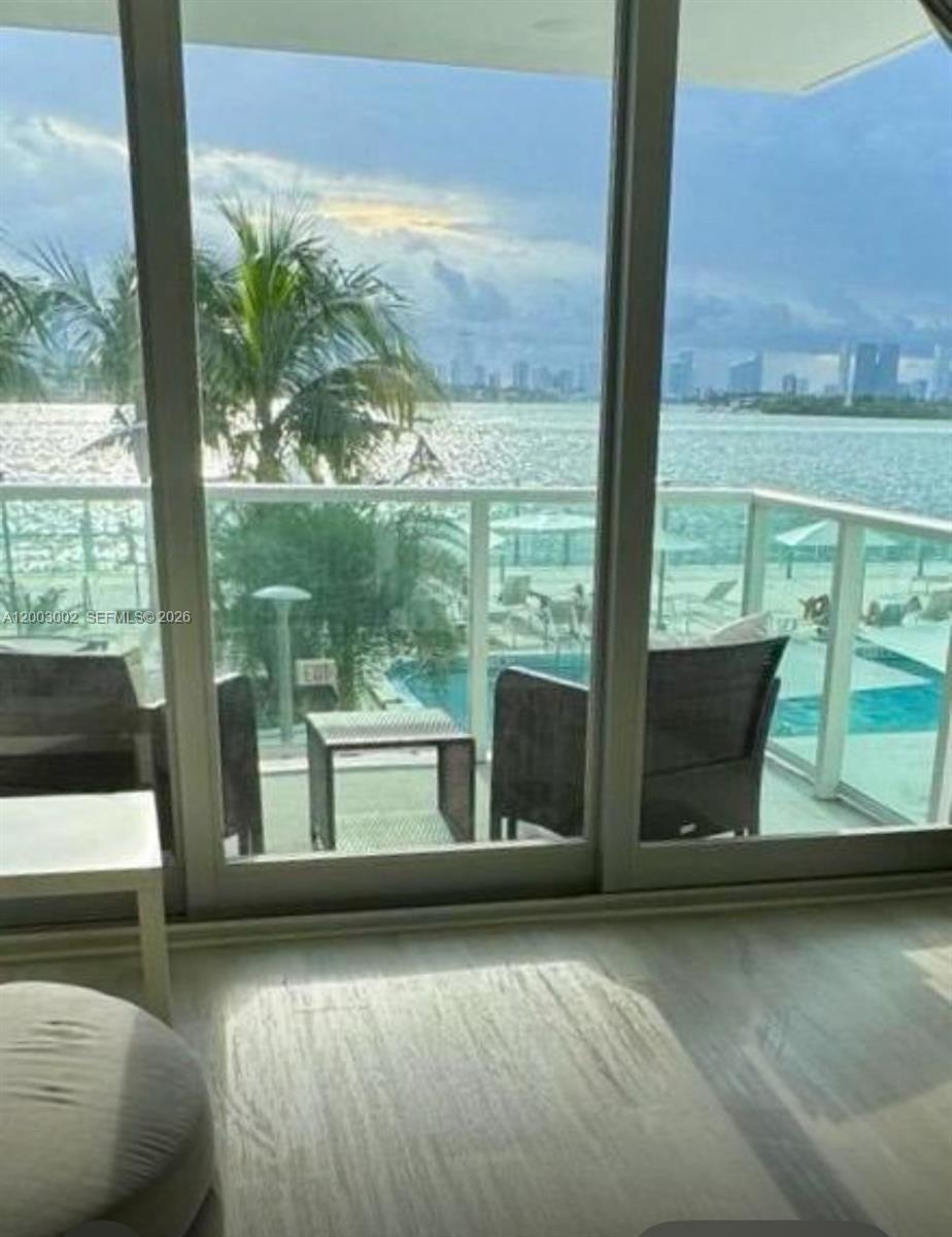 A view of a pool and bay from inside a room with sliding glass doors — 1000 West Ave # 218, Miami Beach FL 33139, MIAMI BEACH, FL