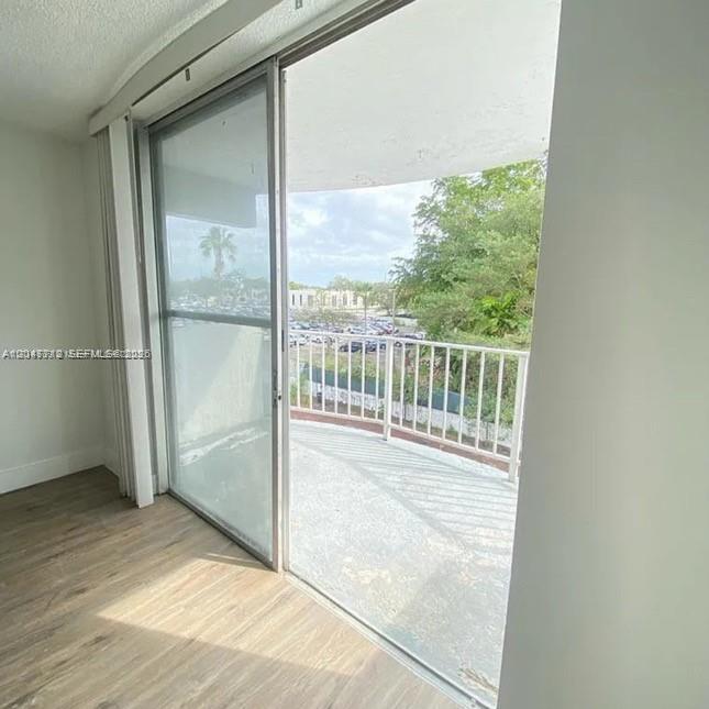 A room with wood-look flooring features a sliding glass door leading to a balcony — 492 NW 165th St Rd # 415, Miami FL 33169, MIAMI, FL
