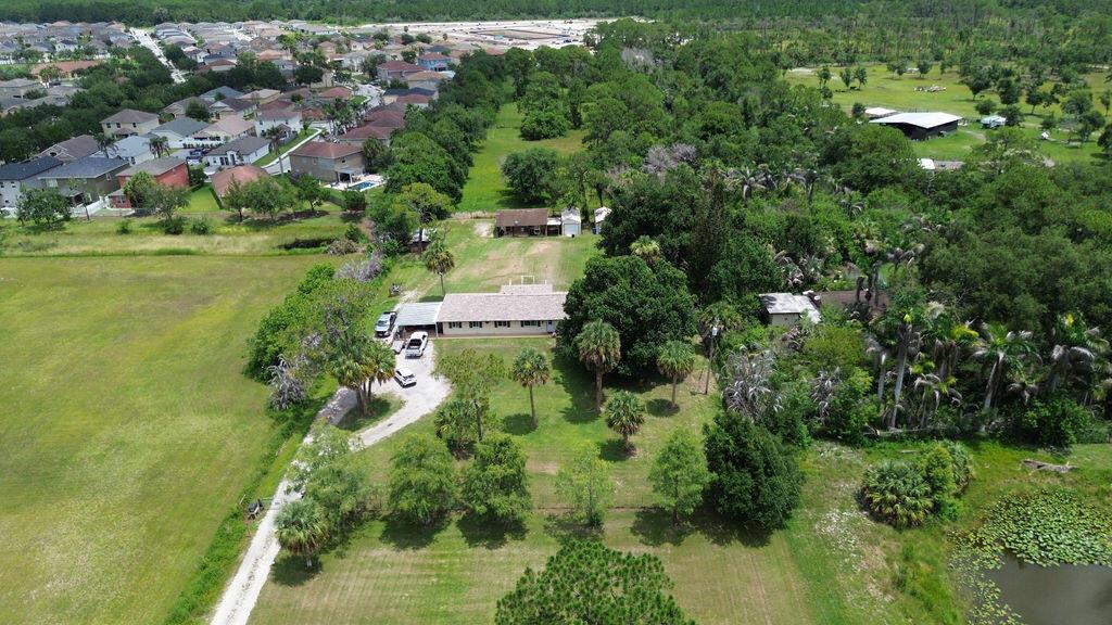 An aerial view shows a house with a large yard, trees, and a nearby neighborhood — 9302 Orange Avenue, Fort Pierce FL 34945, FORT PIERCE, FL
