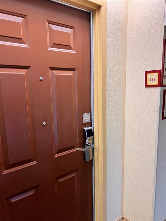 A brown door with a digital lock and a room number sign on the wall — 3000 MAINGATE LANE UNIT 415, KISSIMMEE, FL