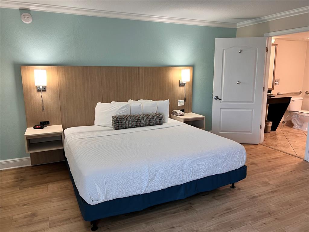 A hotel room features a king bed with a wood headboard and an attached bathroom — 3000 MAINGATE LANE UNIT 415, KISSIMMEE, FL