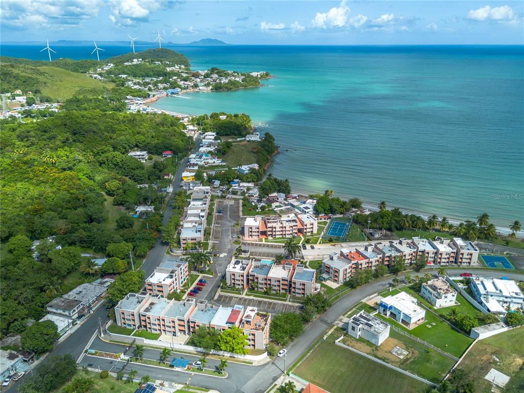 An aerial view shows a coastal residential complex with multi-story buildings near a beach — Cala de Hucares CARR 3 KM 66.7 UNIT B-208, NAGUABO, PR