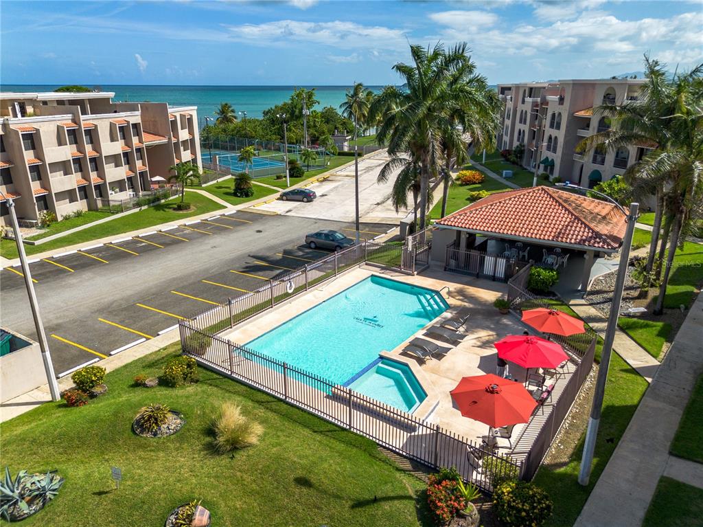An aerial view shows a swimming pool, patio with umbrellas, parking lot, and apartment buildings — Cala de Hucares CARR 3 KM 66.7 UNIT B-208, NAGUABO, PR