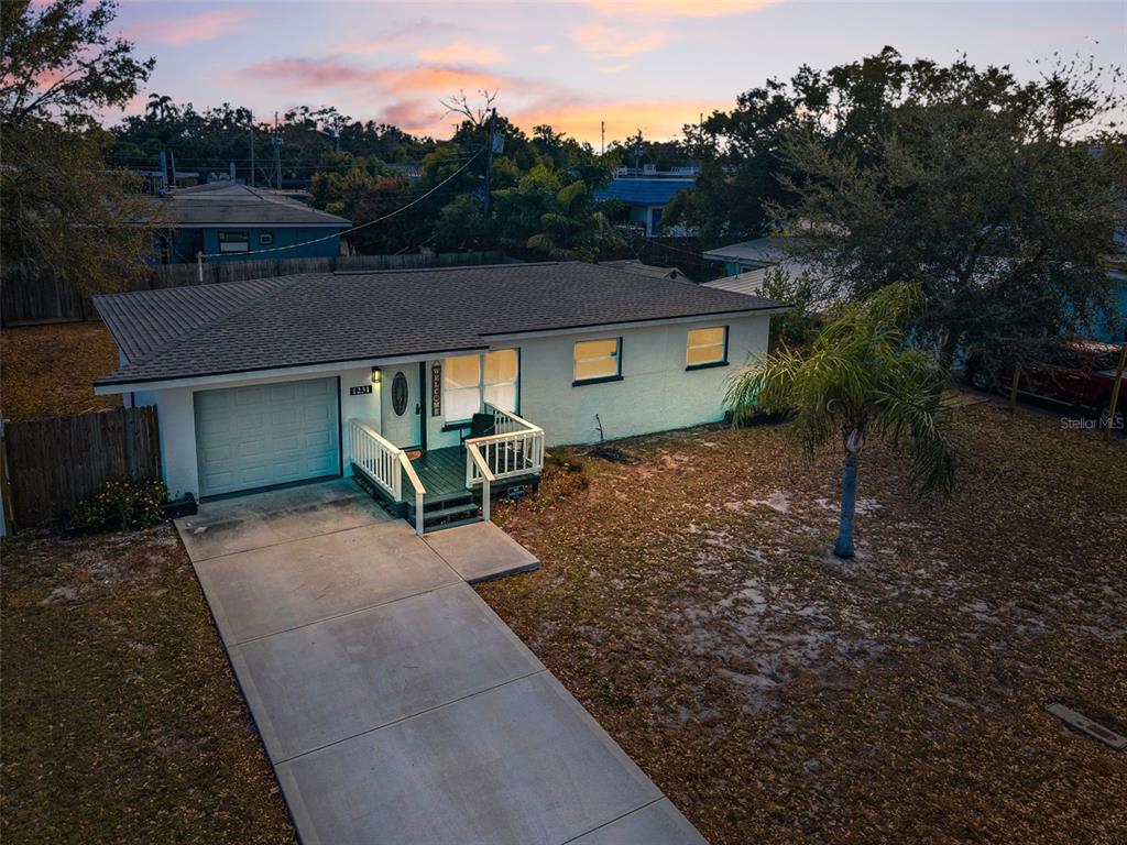 An aerial view of a single-story house with a white exterior, garage, and front porch — 1231 LITTLE JOHN LANE, DUNEDIN, FL