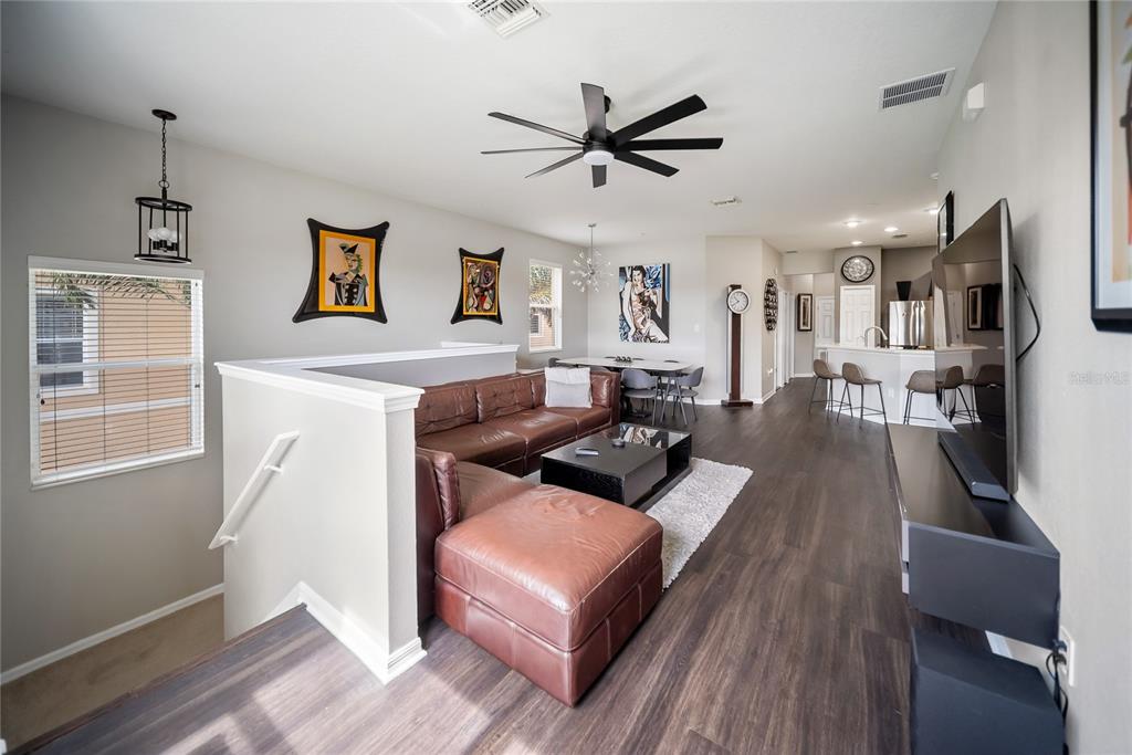 An open-concept living and dining area features a brown leather sectional, dark flooring, and kitchen — 3760 PARKRIDGE CIRCLE UNIT 23-204, SARASOTA, FL