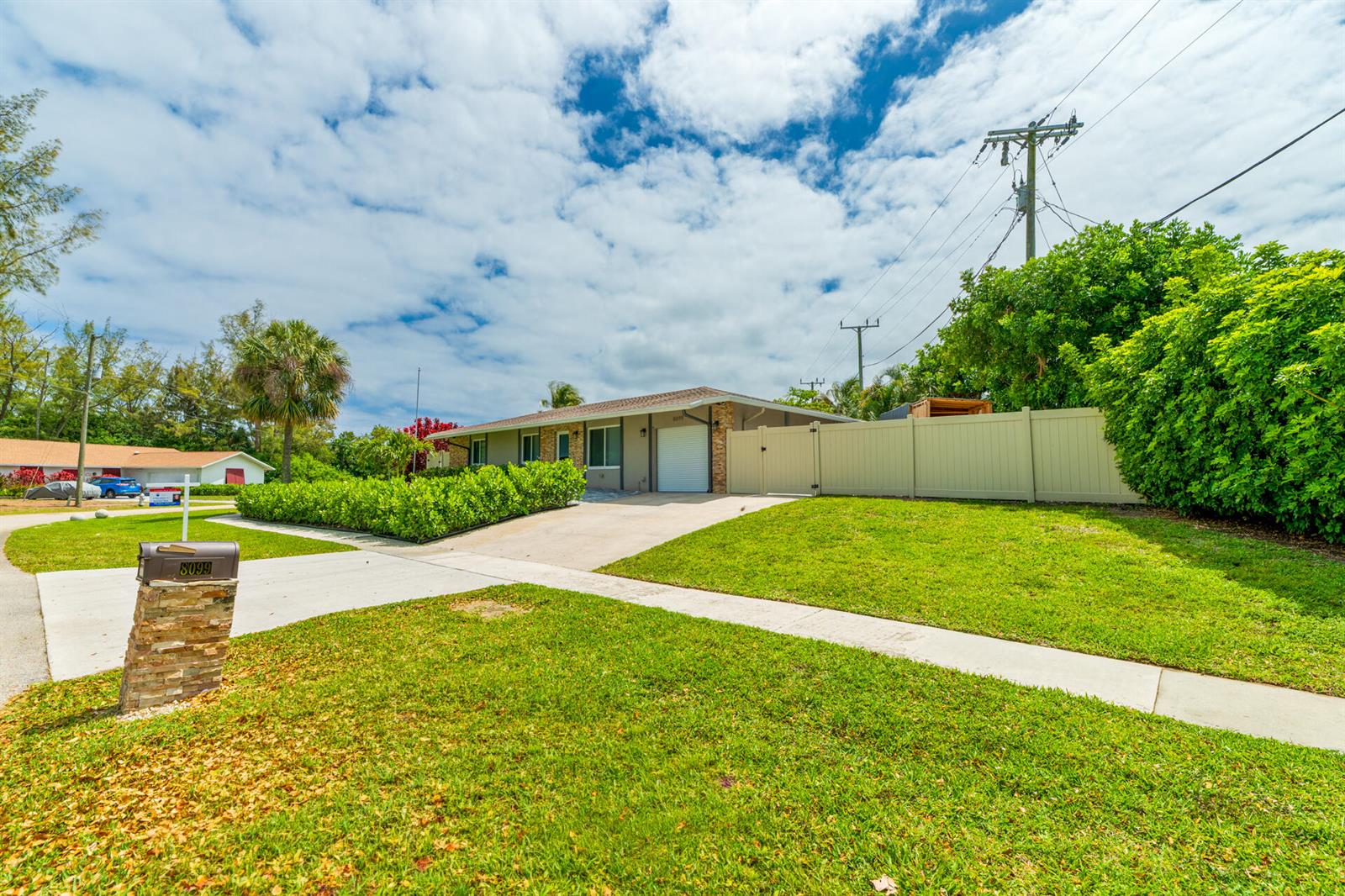 A single-story house with a concrete driveway, a stone mailbox, and a tan privacy fence — 8099 Santa Fe Trail, Boca Raton FL 33487, BOCA RATON, FL