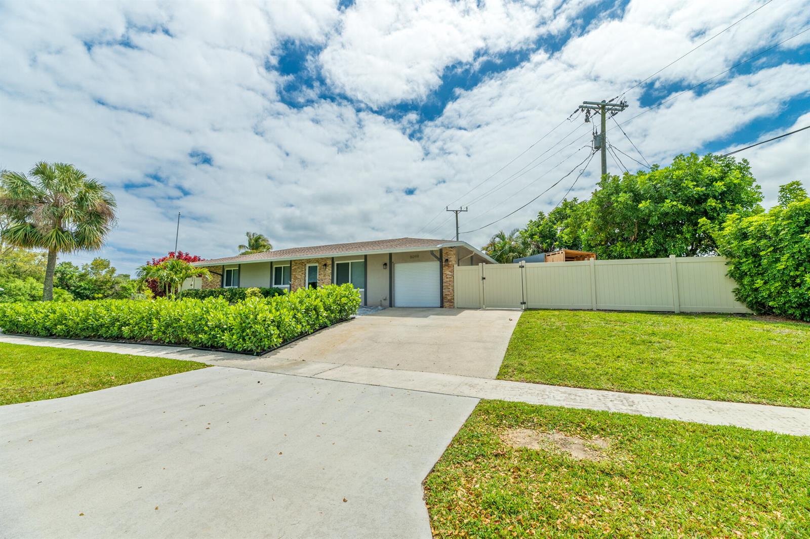 A single-story house with a white garage door, a concrete driveway, and a privacy fence — 8099 Santa Fe Trail, Boca Raton FL 33487, BOCA RATON, FL