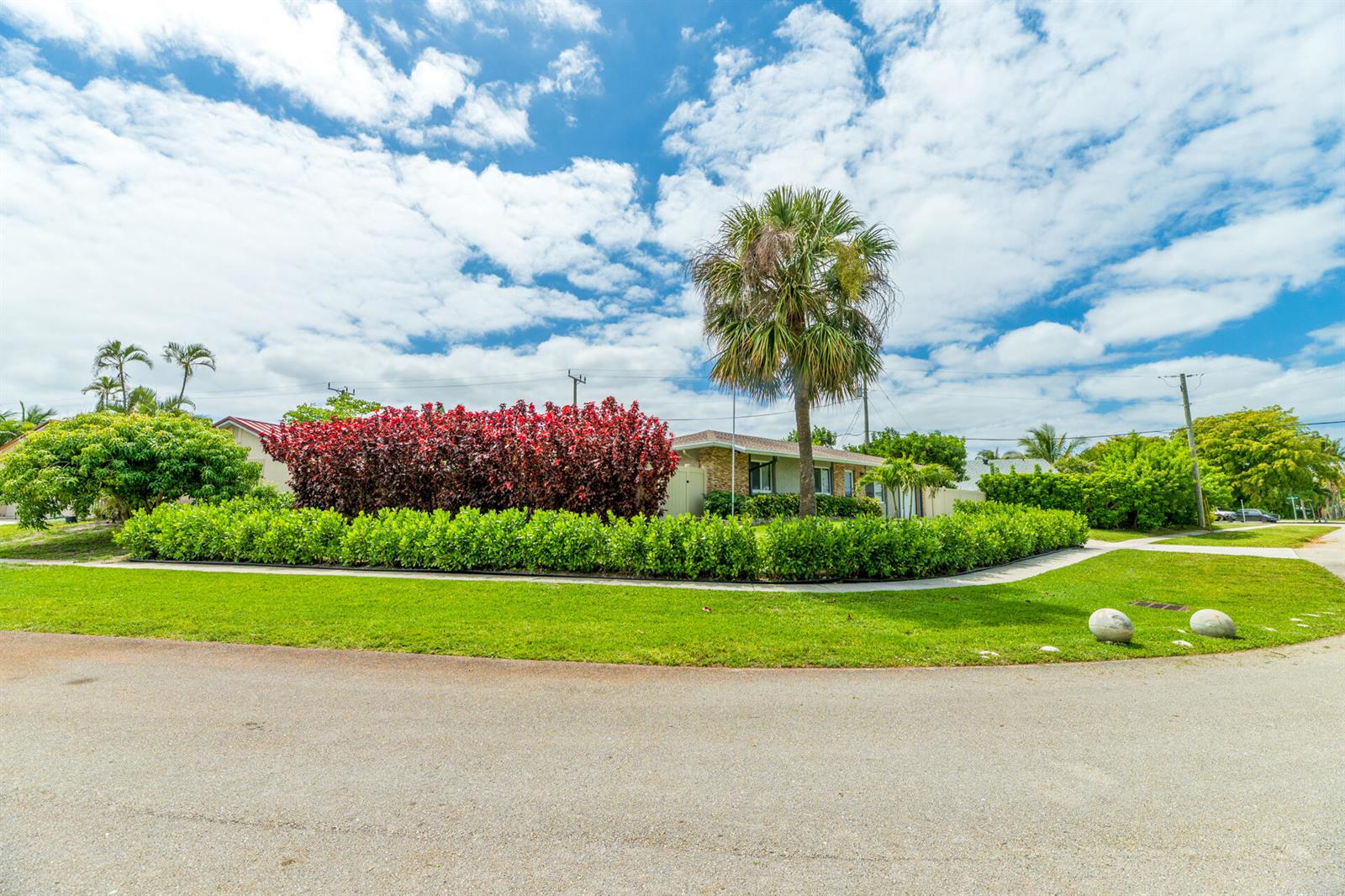 A single-story house is partially obscured by a large red hedge and a palm tree — 8099 Santa Fe Trail, Boca Raton FL 33487, BOCA RATON, FL