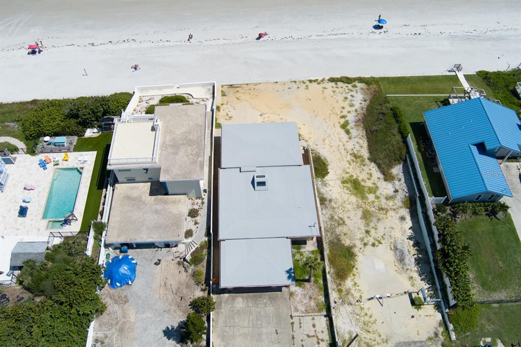 An aerial view shows three beachfront properties with sandy yards and a blue-roofed house — 4207 S ATLANTIC AVENUE, PORT ORANGE, FL