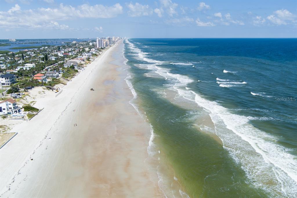 An aerial view of a sandy beach coastline with ocean waves and nearby residential buildings — 4207 S ATLANTIC AVENUE, PORT ORANGE, FL