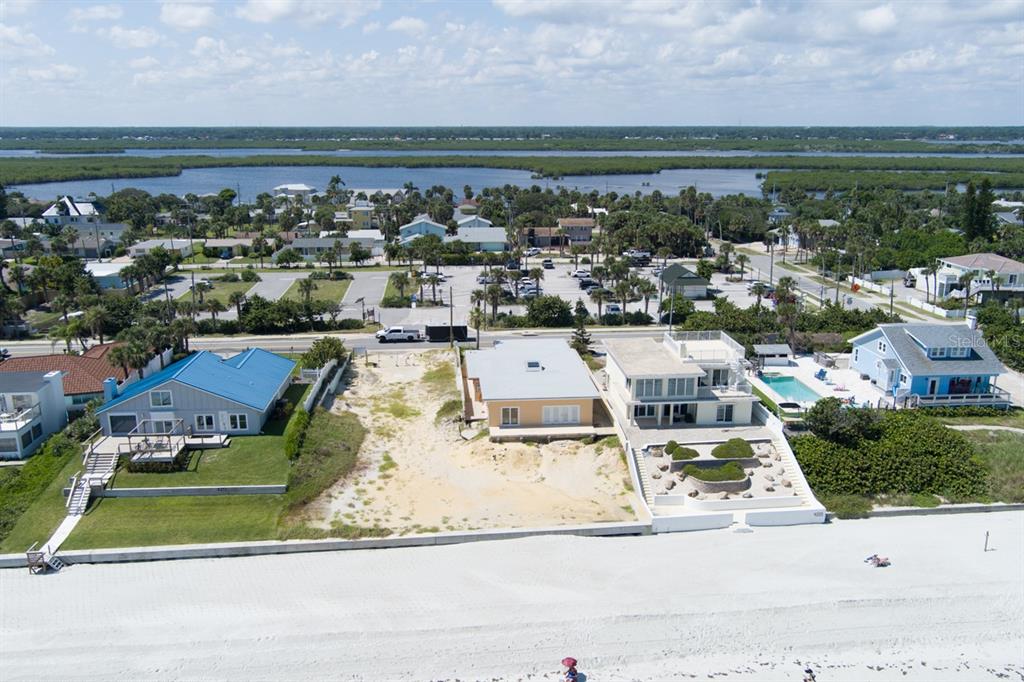 An aerial view shows three beachfront houses, one of which is an empty sandy lot — 4207 S ATLANTIC AVENUE, PORT ORANGE, FL