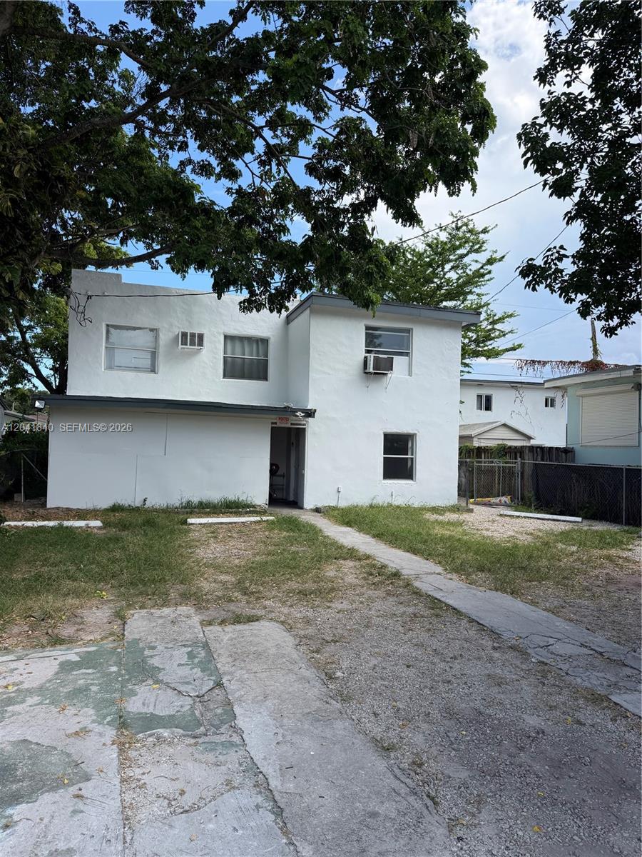 A two-story white stucco building features a flat roof, window air conditioning units, and a driveway — 1832 NW 46th St # l, Miami FL 33142, MIAMI, FL