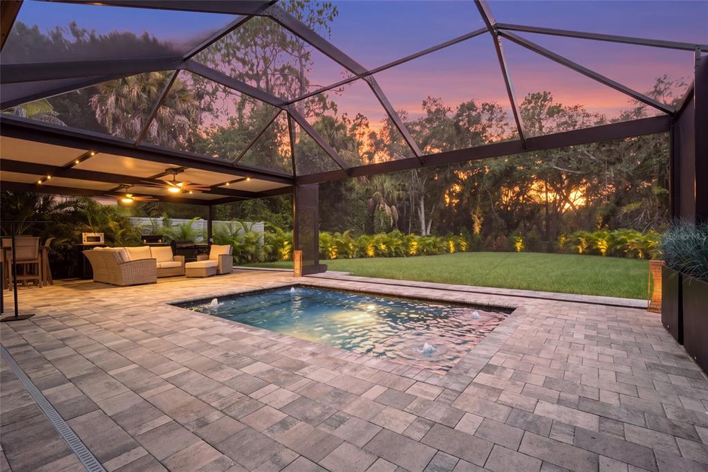 A screened-in patio features a rectangular swimming pool, stone pavers, and outdoor lounge furniture — 13622 11TH TERRACE E, BRADENTON, FL