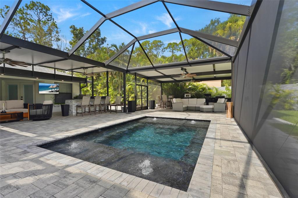 A screened-in patio features a rectangular swimming pool, outdoor kitchen, and lounge seating area — 13622 11TH TERRACE E, BRADENTON, FL