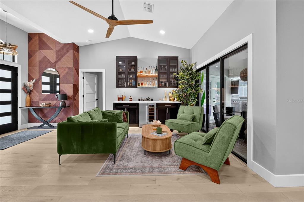 A living room features a green sofa, two armchairs, a wet bar, and wood flooring — 13622 11TH TERRACE E, BRADENTON, FL