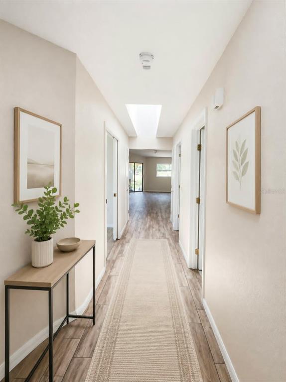 A hallway with light wood-look flooring, a console table, and framed wall art — 1203 SAXONY CIRCLE UNIT A, PUNTA GORDA, FL