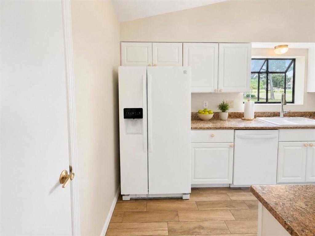 A white refrigerator stands next to white cabinets and a granite countertop in a kitchen — 1203 SAXONY CIRCLE UNIT A, PUNTA GORDA, FL