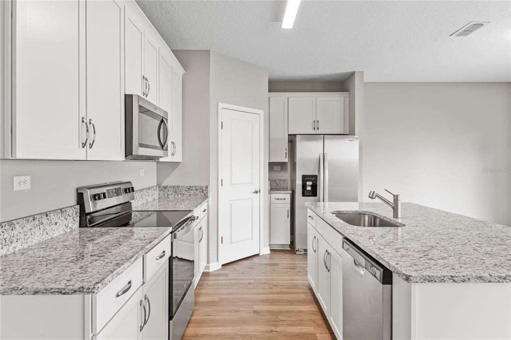 A modern kitchen features white cabinets, granite countertops, stainless steel appliances, and a center island — 3905 HOLSTEIN WAY, GREEN COVE SPRINGS, FL