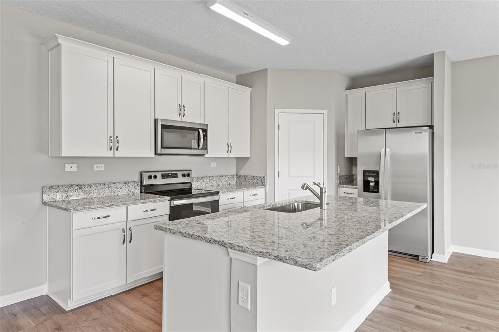 A kitchen with white cabinets, granite countertops, stainless steel appliances, and a central island — 3905 HOLSTEIN WAY, GREEN COVE SPRINGS, FL