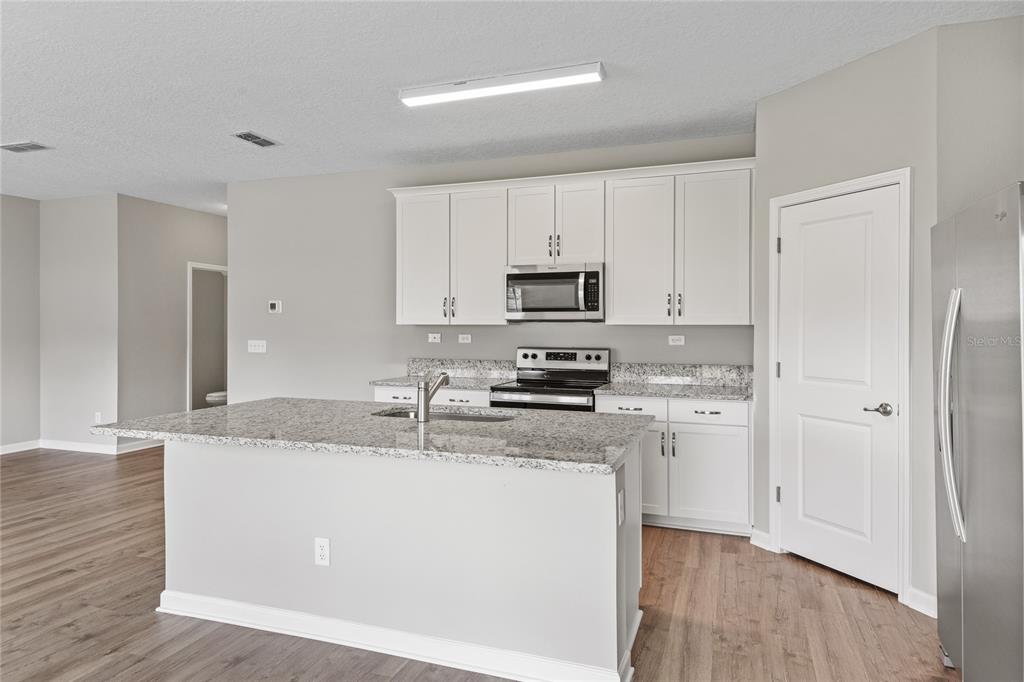 A kitchen with white cabinets, granite countertops, a center island, and stainless steel appliances — 3905 HOLSTEIN WAY, GREEN COVE SPRINGS, FL