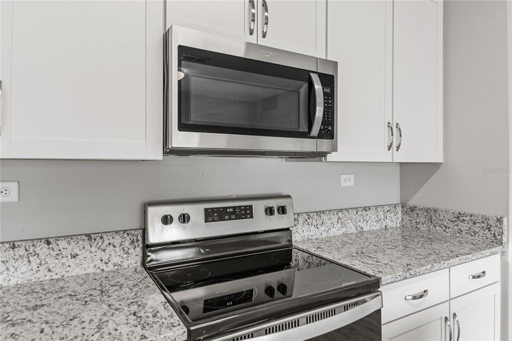 A kitchen features white cabinets, granite countertops, and stainless steel appliances — 3905 HOLSTEIN WAY, GREEN COVE SPRINGS, FL
