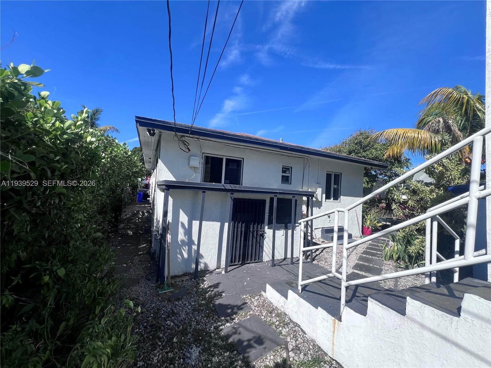 The exterior of a white house features a covered entryway, metal railings, and gravel landscaping — 22 NE 51st St # 2, Miami FL 33137, MIAMI, FL
