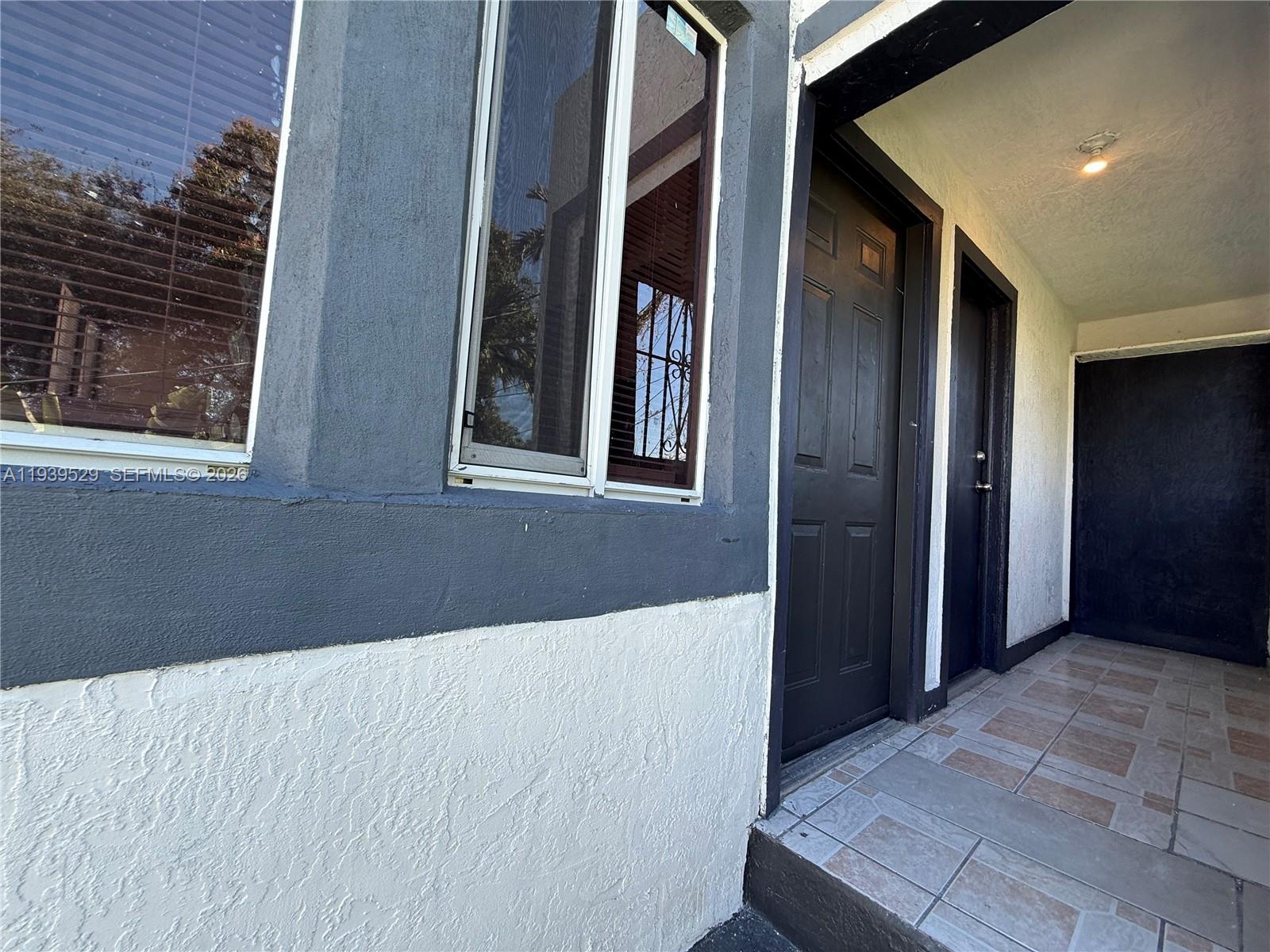 A view of a building exterior featuring a tiled porch, two dark doors, and windows — 22 NE 51st St # 2, Miami FL 33137, MIAMI, FL