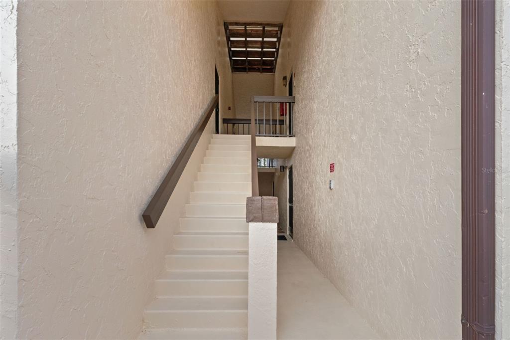 An outdoor concrete staircase leads to an upper-level landing between two beige stucco walls — 19505 QUESADA AVENUE UNIT S208, PORT CHARLOTTE, FL