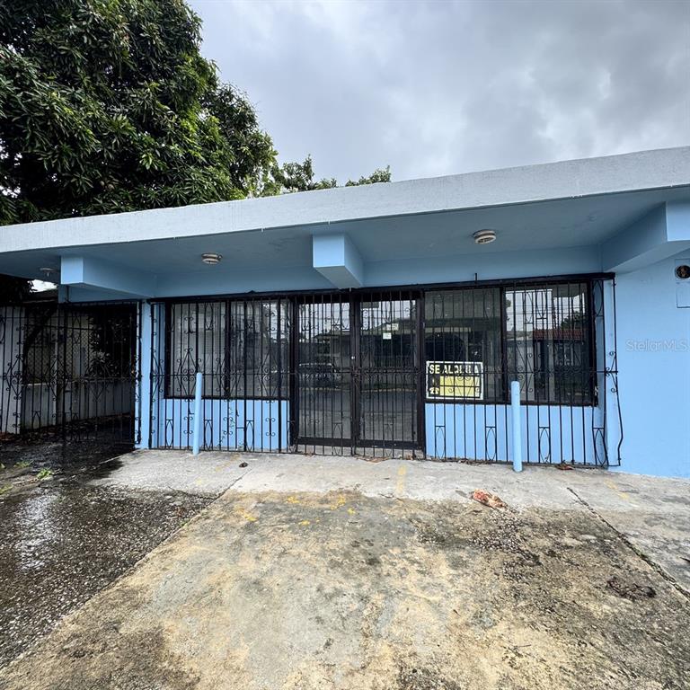 A light blue commercial building exterior features a concrete overhang and black metal security bars — Calle 3 URB. FLAMBOYAN UNIT A-3, MANATI, PR