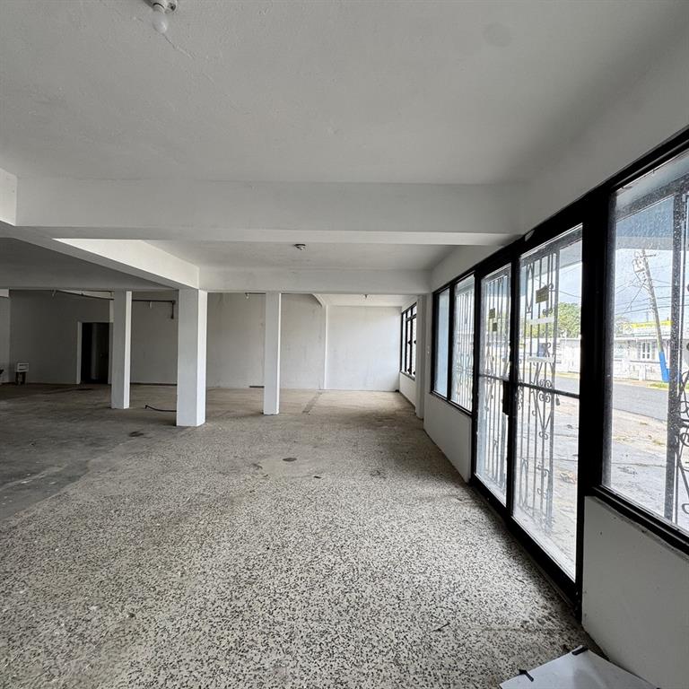 An empty commercial space features concrete floors, white pillars, and large glass storefront windows — Calle 3 URB. FLAMBOYAN UNIT A-3, MANATI, PR