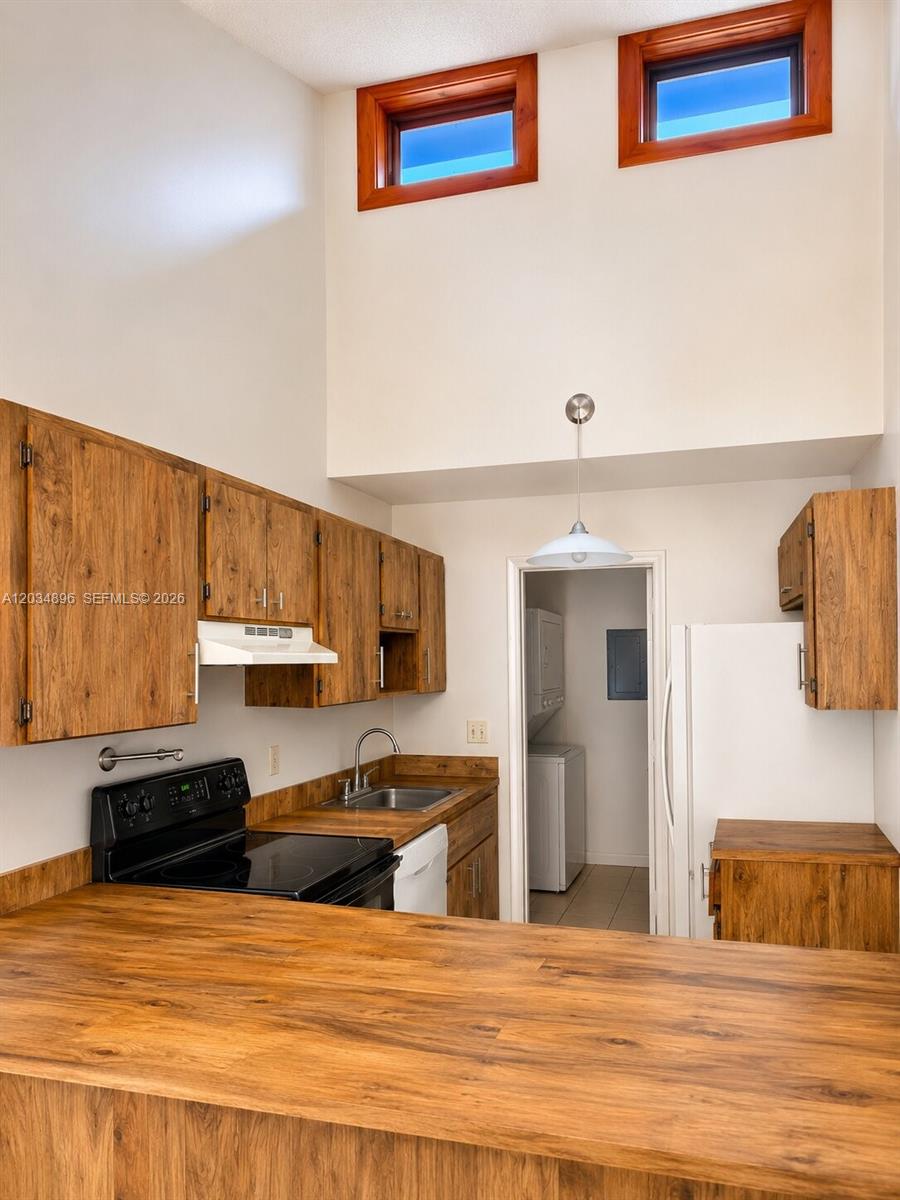 A kitchen features wood-grain cabinets, a black stove, and two high windows — 3819 SW 69th Ave # L, Miramar FL 33023, MIRAMAR, FL